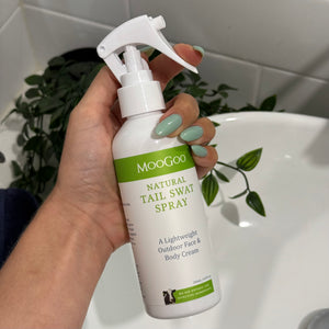 MooGoo Tail Swat Spray shown against a bathroom sink in hand, multipurpose natural spray to hydrate skin and provide outdoor protection against insects for all ages.