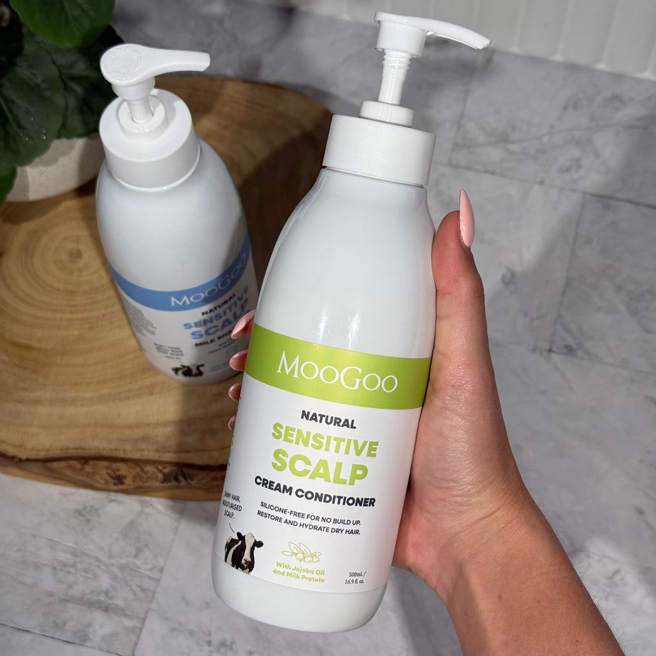 MooGoo Natural Scalp-Friendly Shampoo and Conditioner pack held by woman, gentle hydrating haircare for dandruff prone and sensitive scalp relief