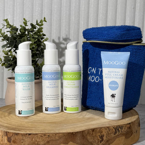 MooGoo Travel Pack on a wooden board with a plant in the background, including travel-sized Milk Shampoo, Cream Conditioner, Milk Wash and Full Cream Moisturiser - ideal for sensitive skin, hydration and scalp health